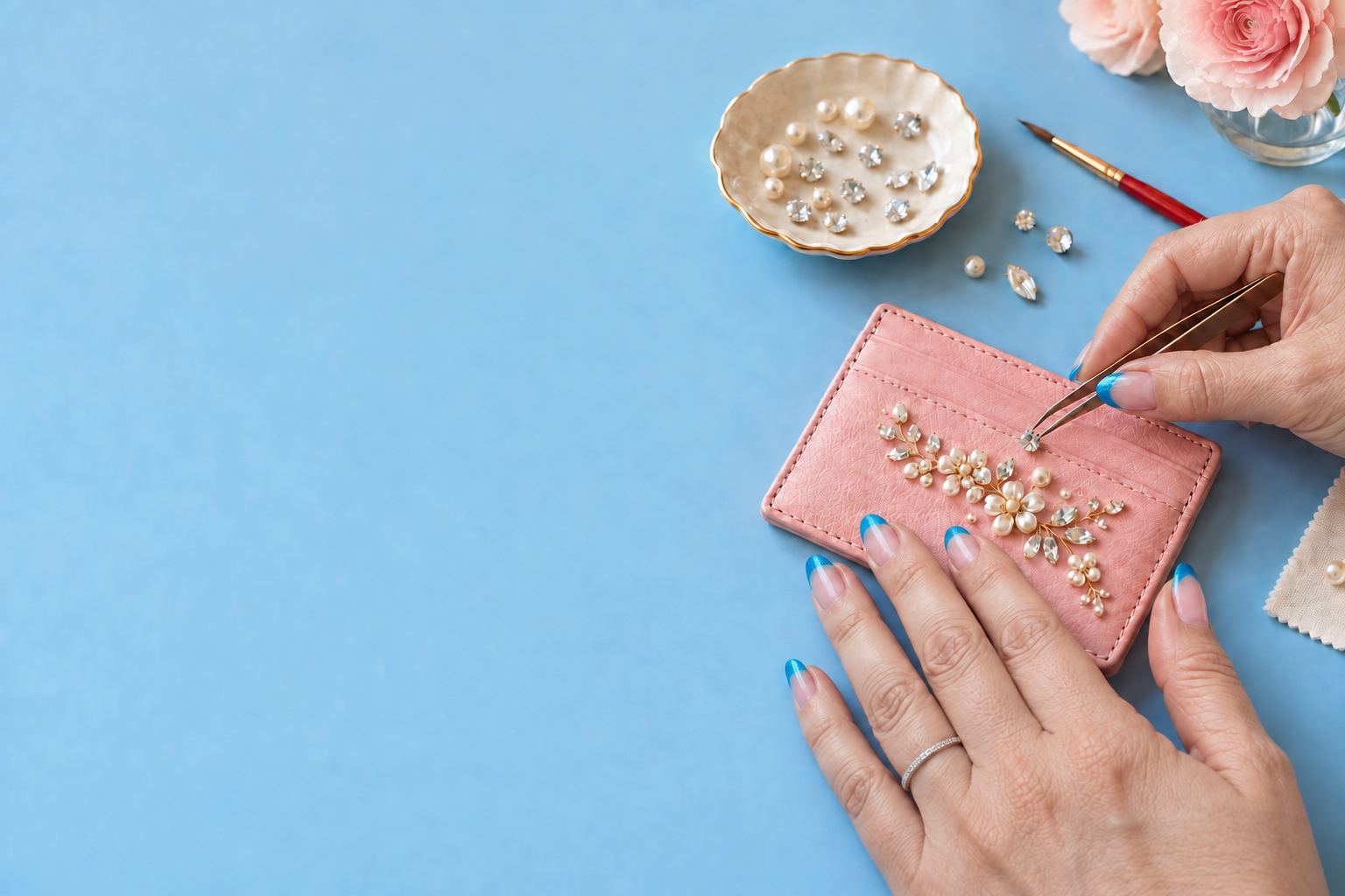 Concept image of hands adding crystals and pearls to a pink cardholder